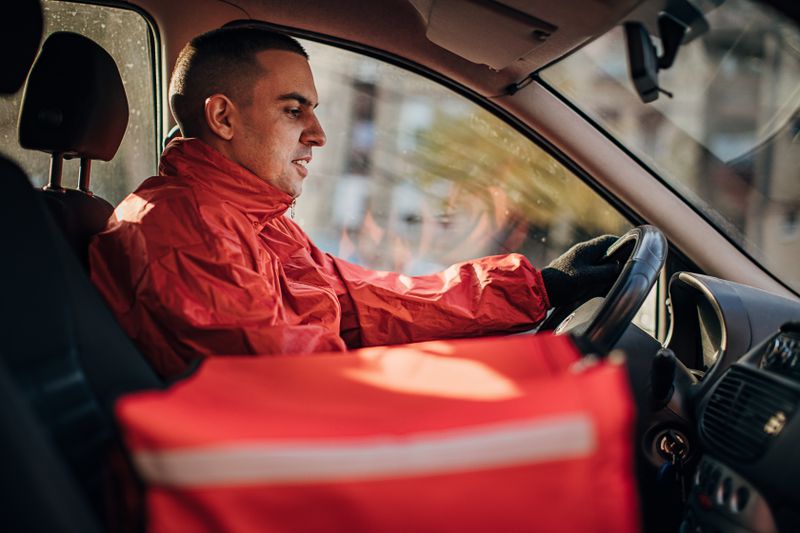 A gig worker in the driver's seat of a delivery vehicle.
