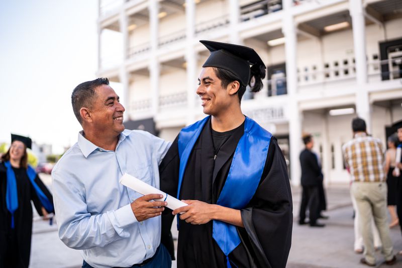 Young graduate man talking with his father on the graduation