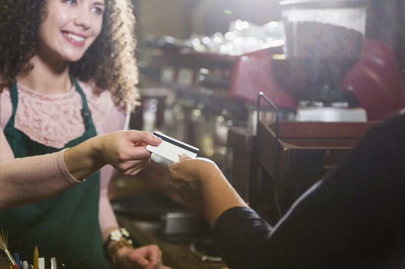Person in apron at coffee shop taking a gift card from a customer