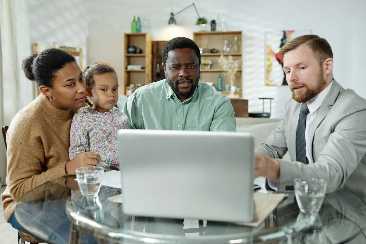 A financial advisor meets with parents and a young child as they discuss suitable investments for a collage fund.