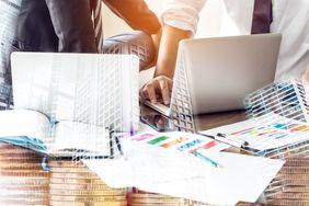 Financial Managers talking in front of laptops on a wooden table. on