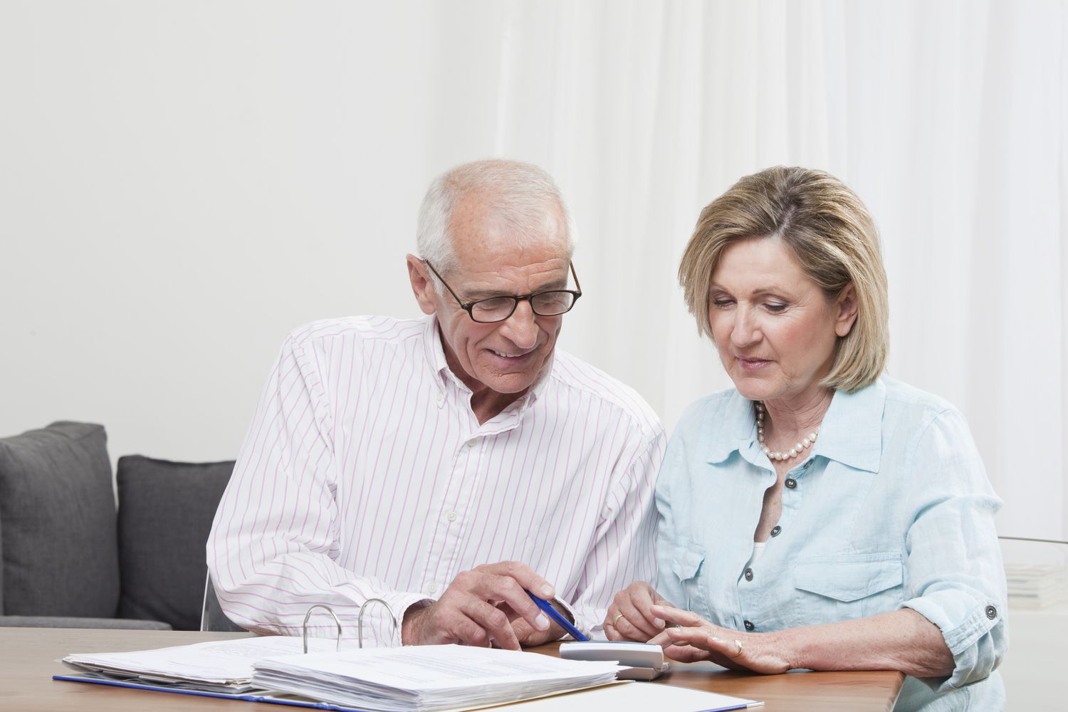 Older couple at home, looking together at financial documents and a calculator