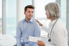 Female doctor discusses paperwork with man in his 30s