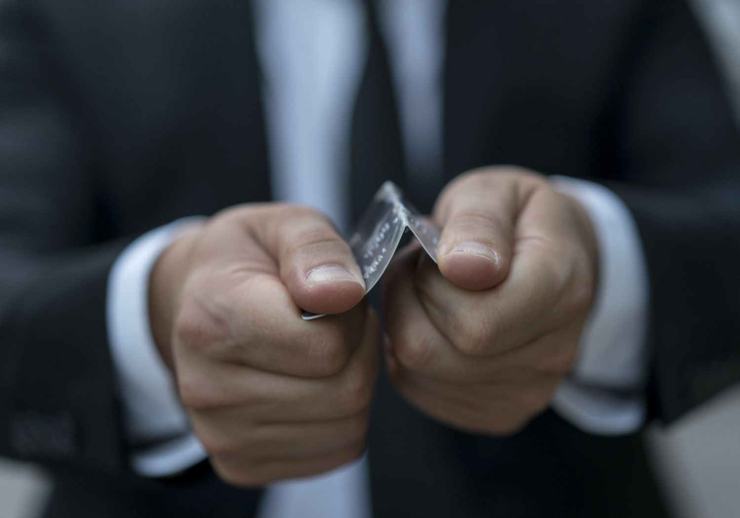 A person breaking a credit card in half to imply that the credit card is cancelled.