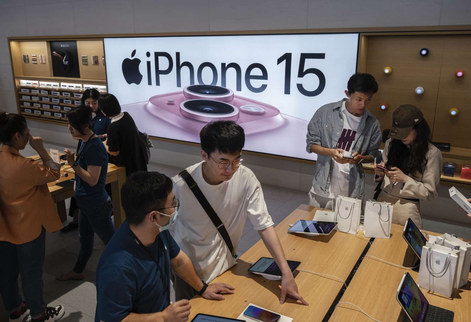 Shoppers looks at an iPhone 15 display in an Apple store.