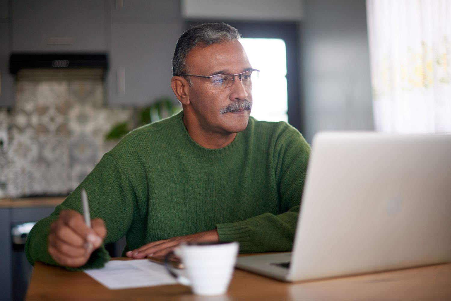 Person in green sweater writing down the best investment options 