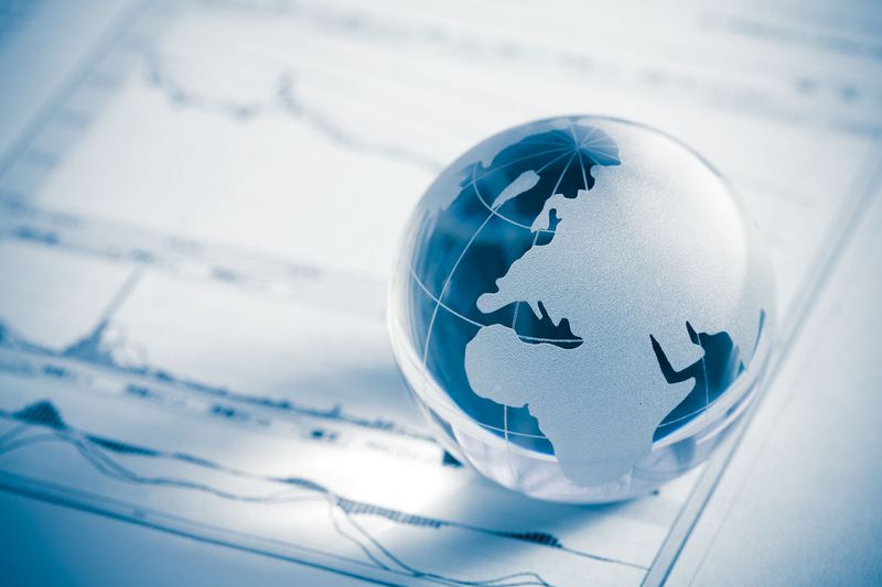 A small globe on top of a stock market chart.