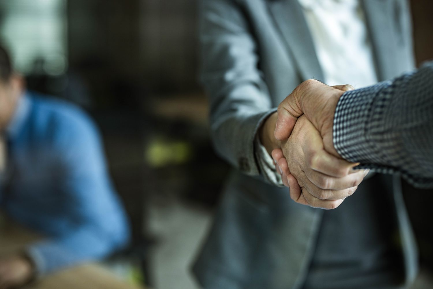 Two company executives shaking hands after completing a company merger.