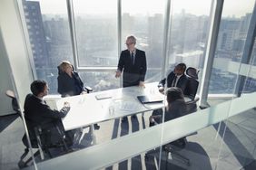 Businessman talking to colleagues in a boardroom meeting with the skyline visible through the windows