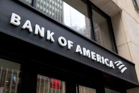 The Bank of America logo is seen in white text on the side of a building above doors and an exit sign.