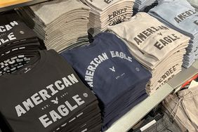 Stacks of American Eagle shirts sit on a display table in a store.