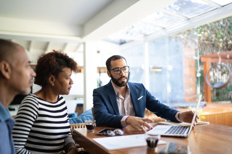 Financial advisor with clients discussing tax-sheltered investment vehicles that minimize tax drag.