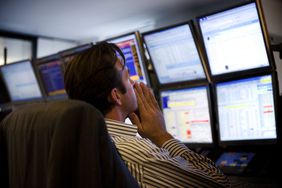 Broker dealer in front of financial market data screens