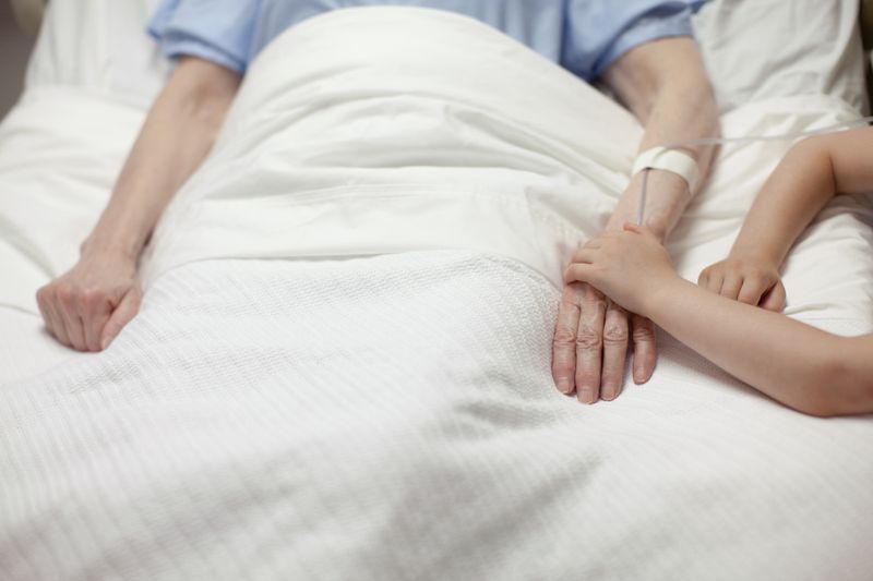 Young girl holding grandma's hand in hospital short term disability