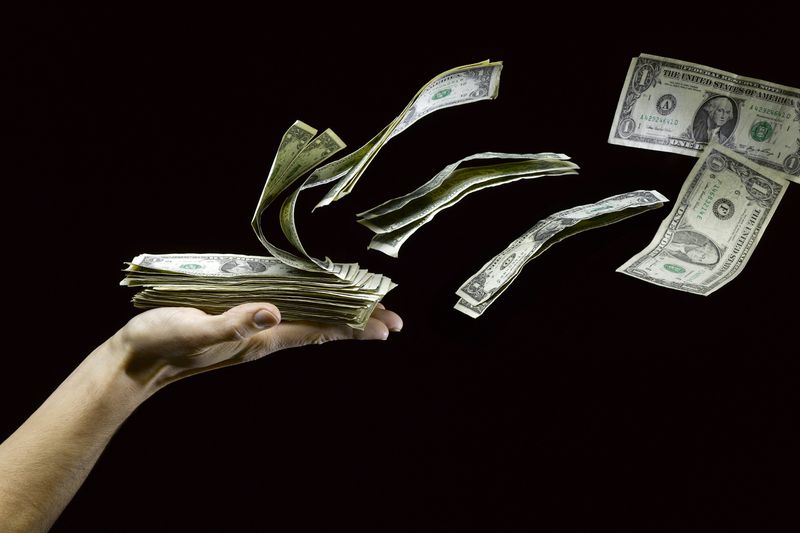 stack of U.S. $1 bills flying out of a person's hands