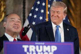 Softbank CEO Masayoshi Son and Donald Trump are seen behind a podium, with part of an American flag visible in the background.