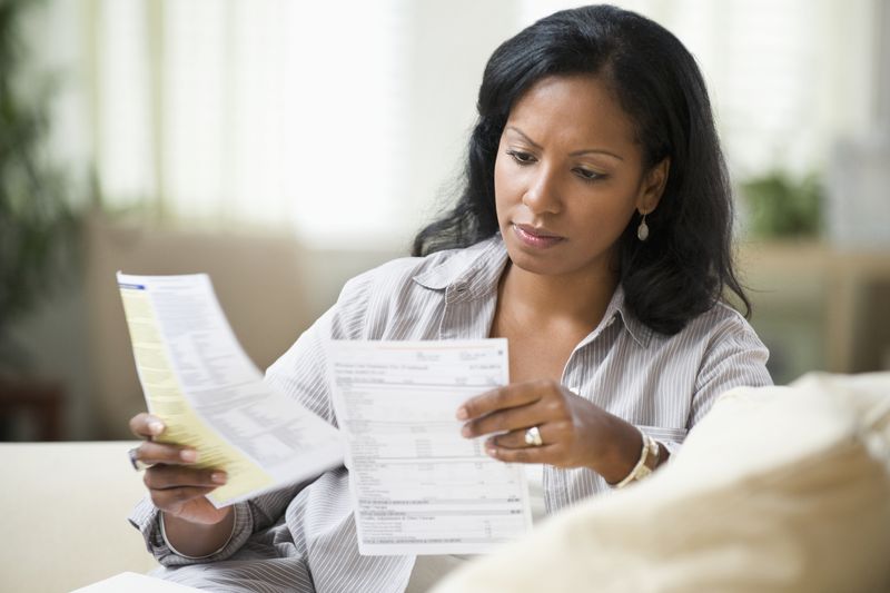 A woman reviews bills and receipts in her home.
