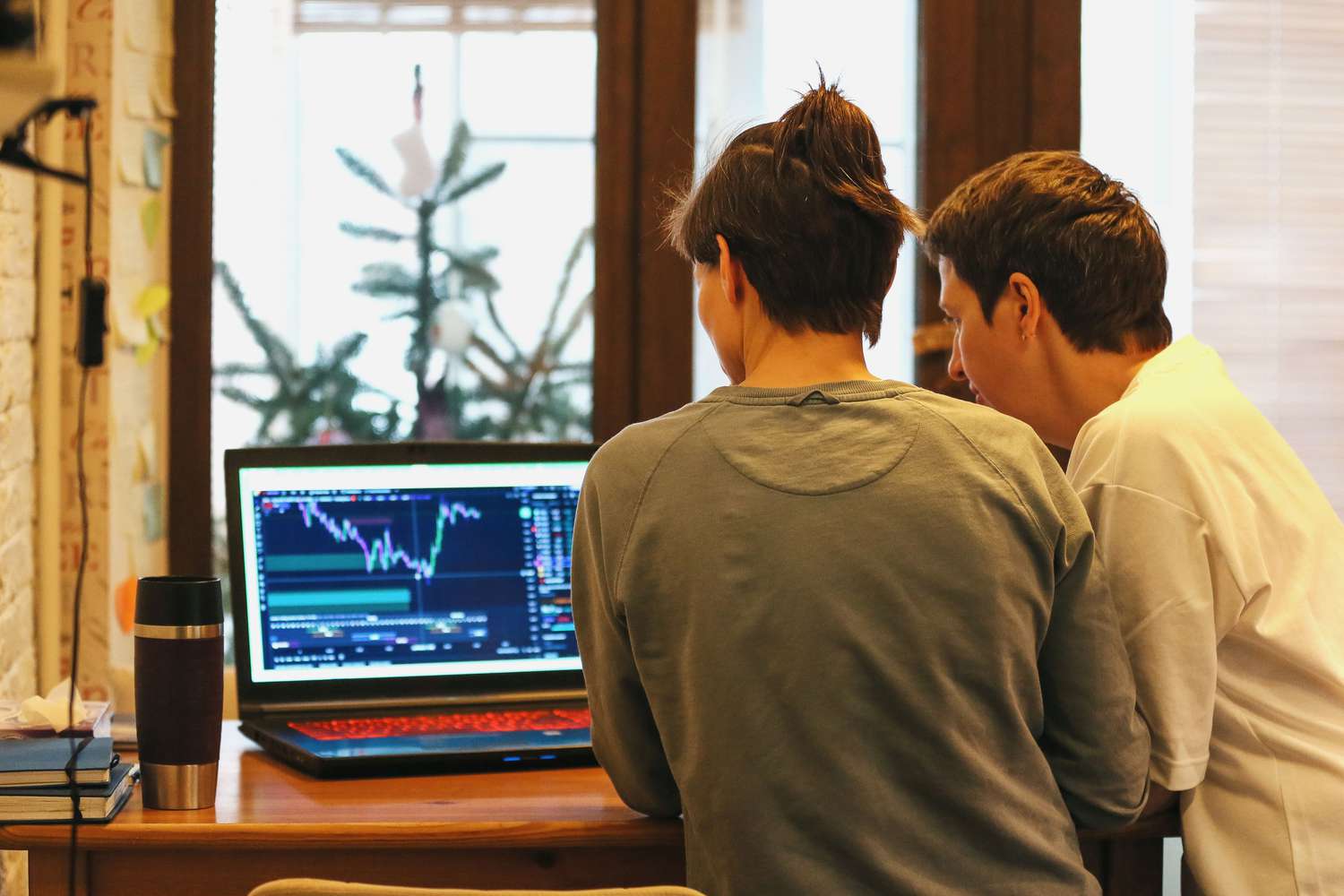 Two people looking at market data on a laptop screen