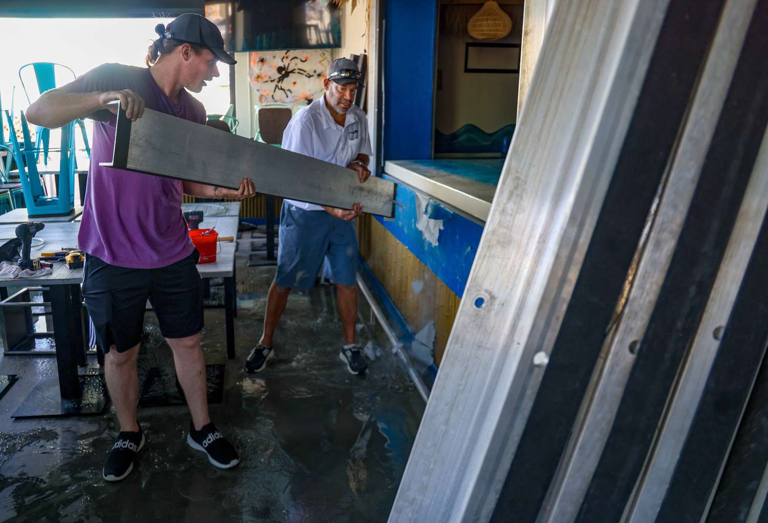 Ft. Myers resident Christopher Boyce Jr, 25, left, assists in the cleanup process at Mr. Wave Island on Fort Myers Beach.