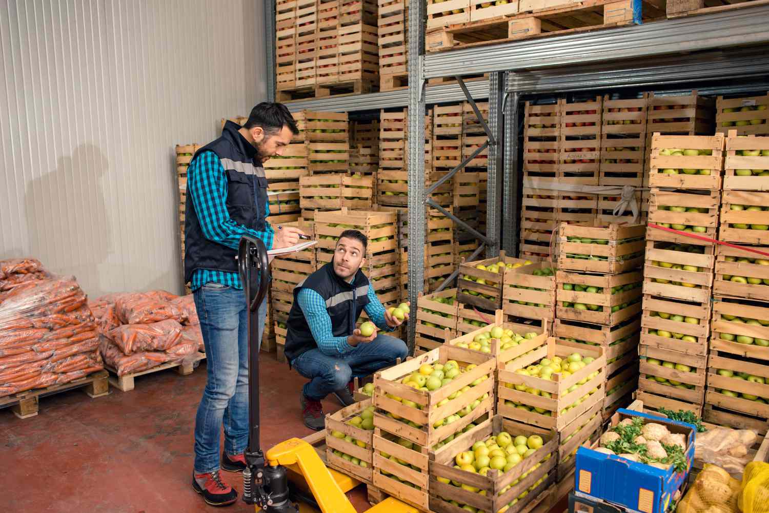 Two workers in a warehouse full of fresh fruits and vegetables
