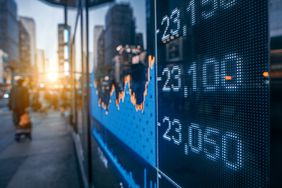 A stock market chart and figures are a displayed on a screen facing the street.