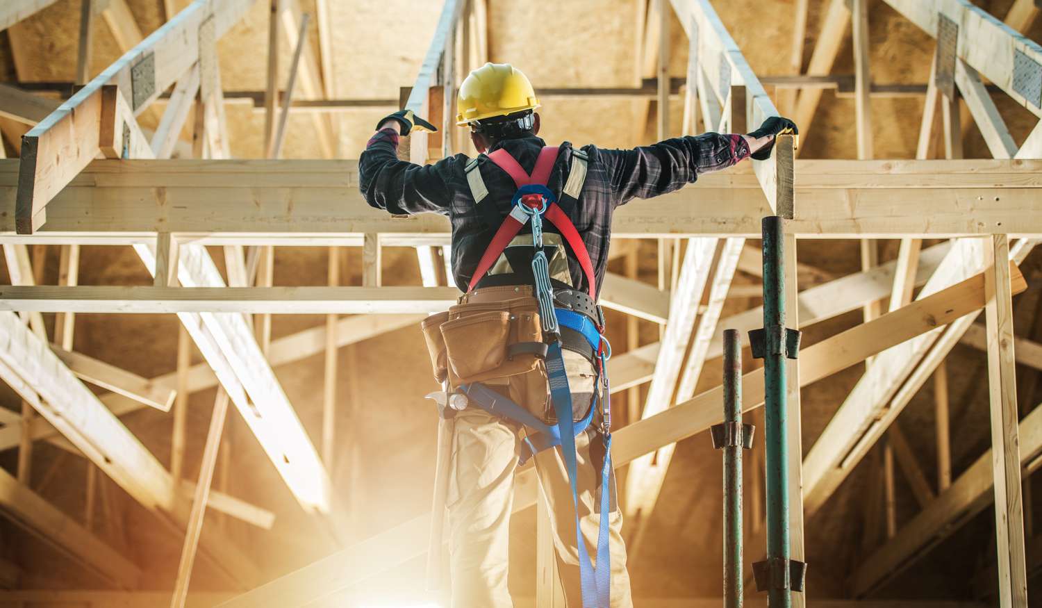 Worker wearing safety harness building a house