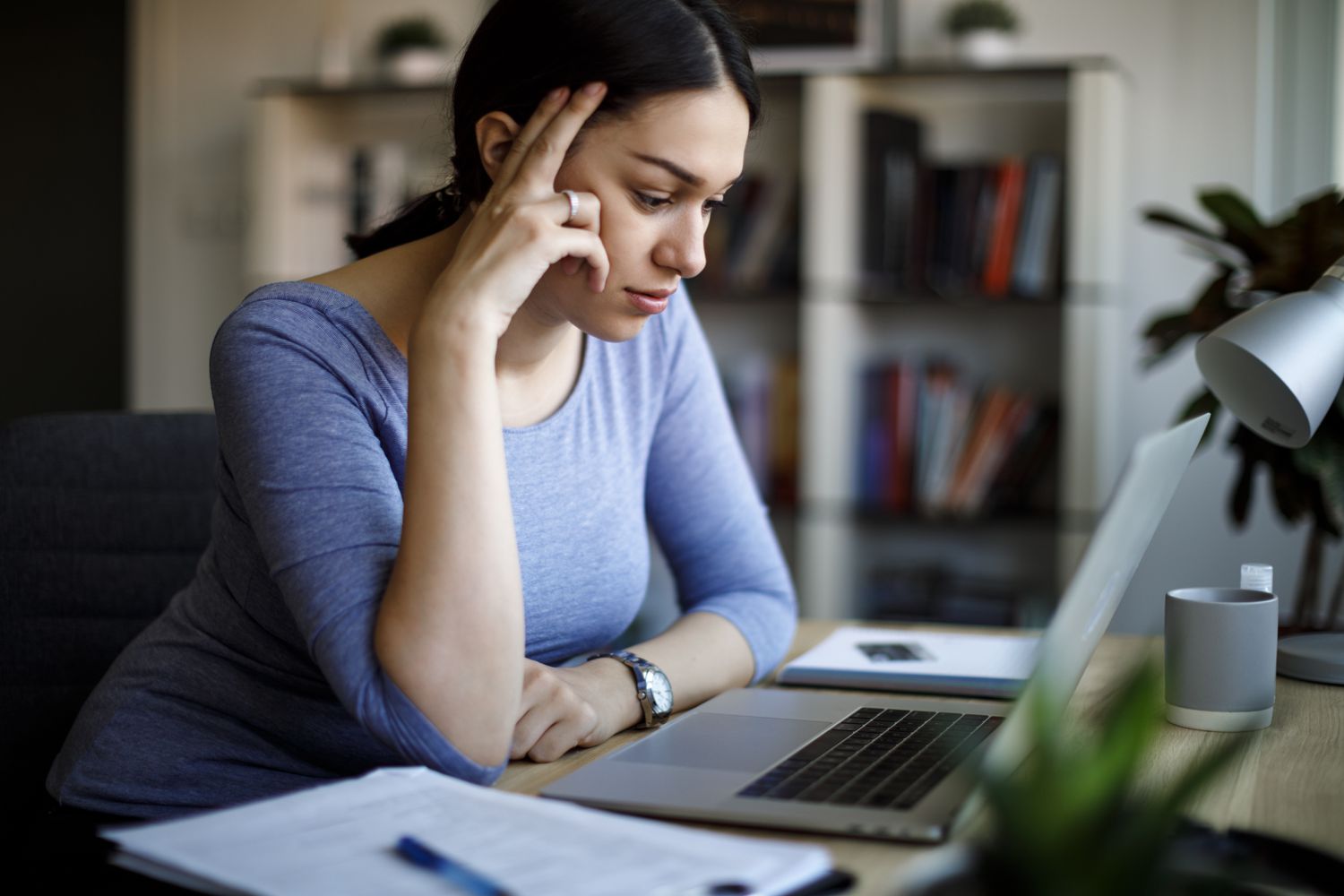 Young Hispanic woman intently studying her laptop at home