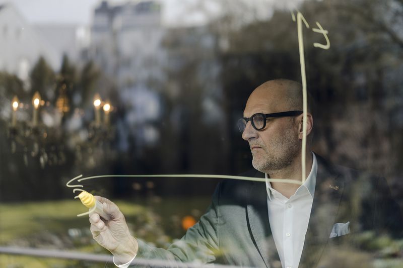 Senior Businessman Brainstorming, Drawing Formulas on Window Pane