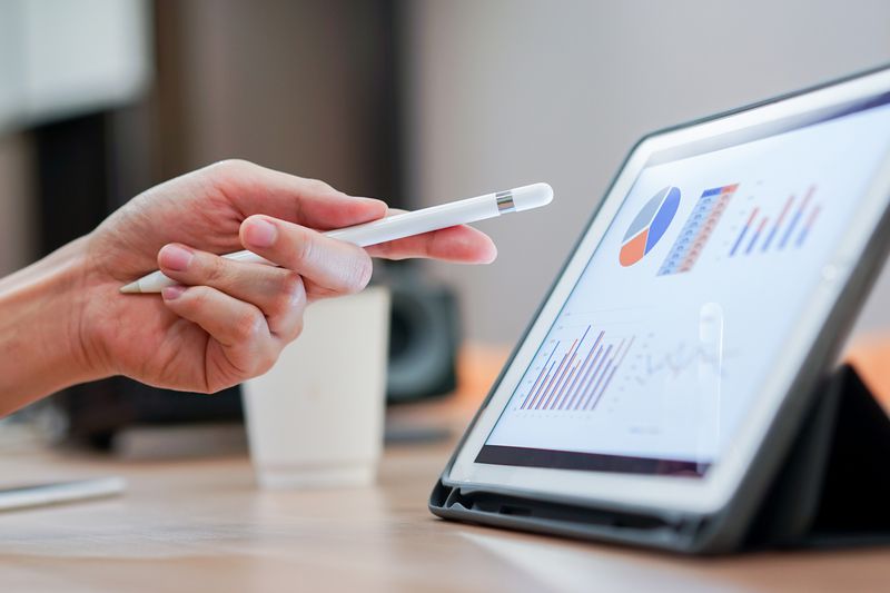 A salesman hand using a stylus pen, pointing on a tablet screen.