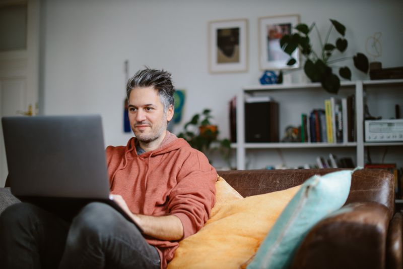 Man working on a laptop on his couch at home