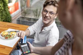 Person paying for a restaurant meal with a credit card