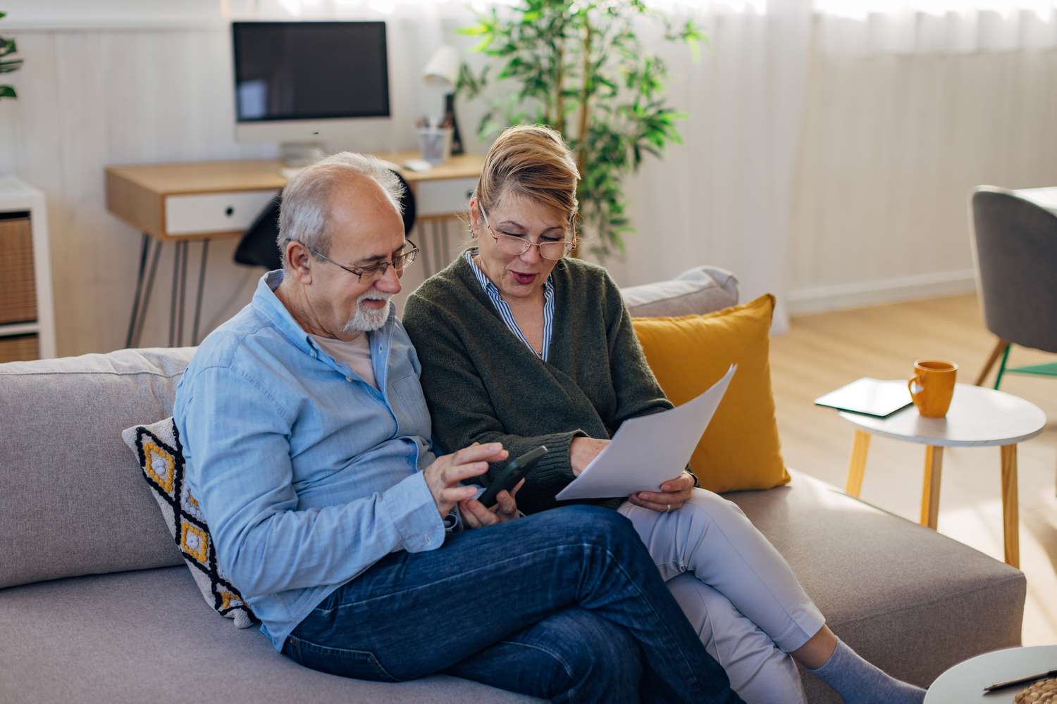 Older couple sitting on their sofa and looking together at mortgage rates and documents