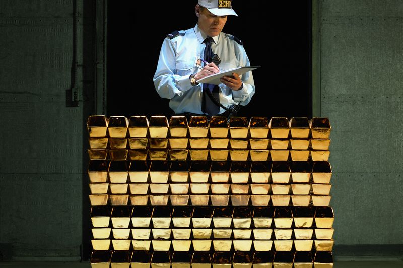 Security guard with clipboard and pen by stack of gold bars.