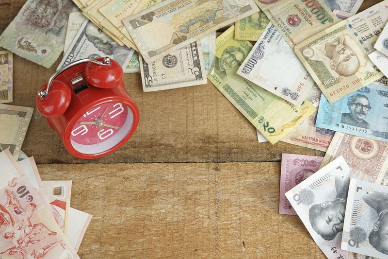 Clock bell and various money from other country with copy space on table
