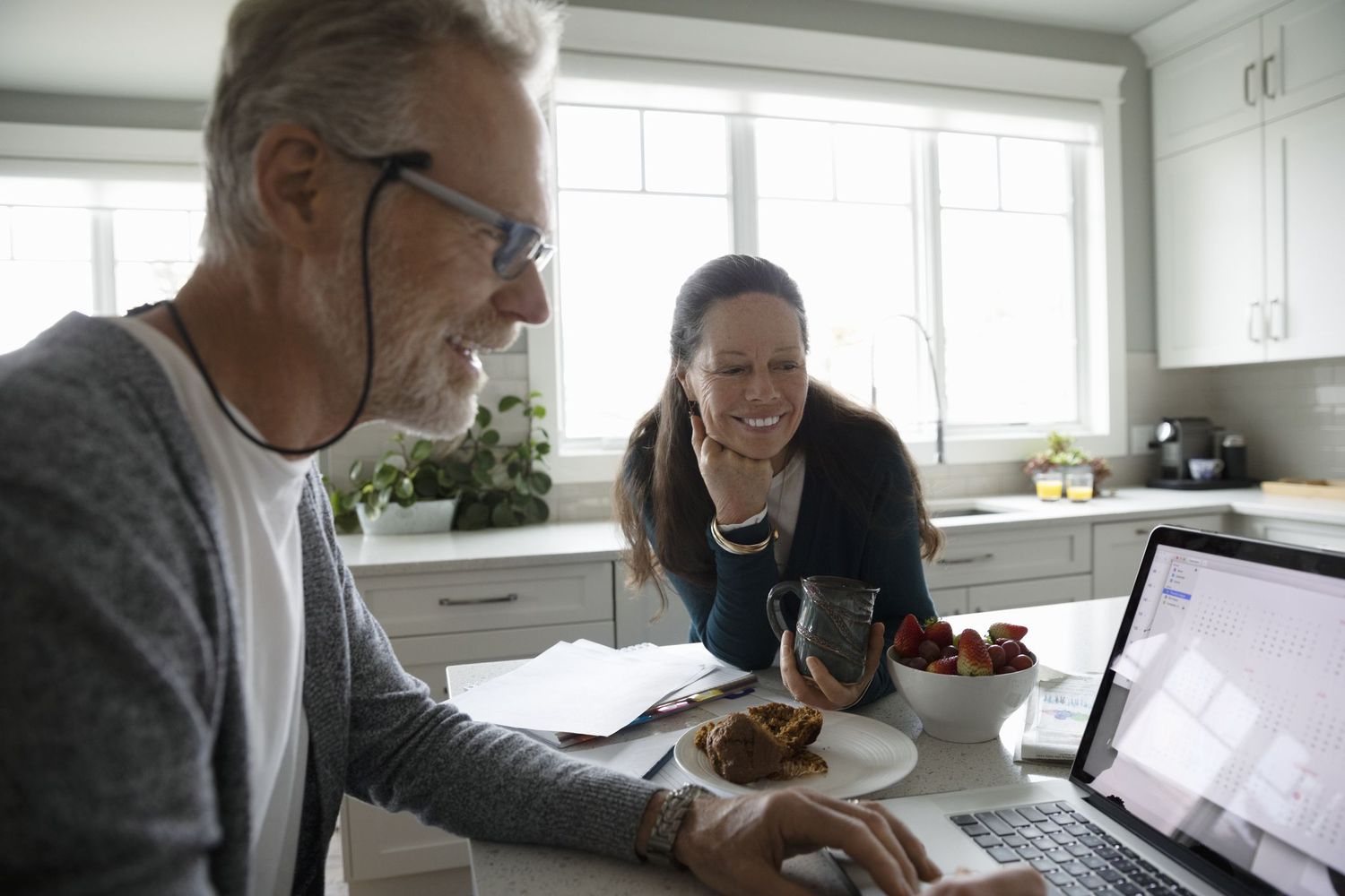 Older couple working on a laptop on the kitchen table