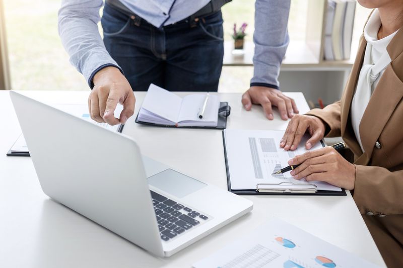 A businessman and colleague discussing over graph on table in office.
