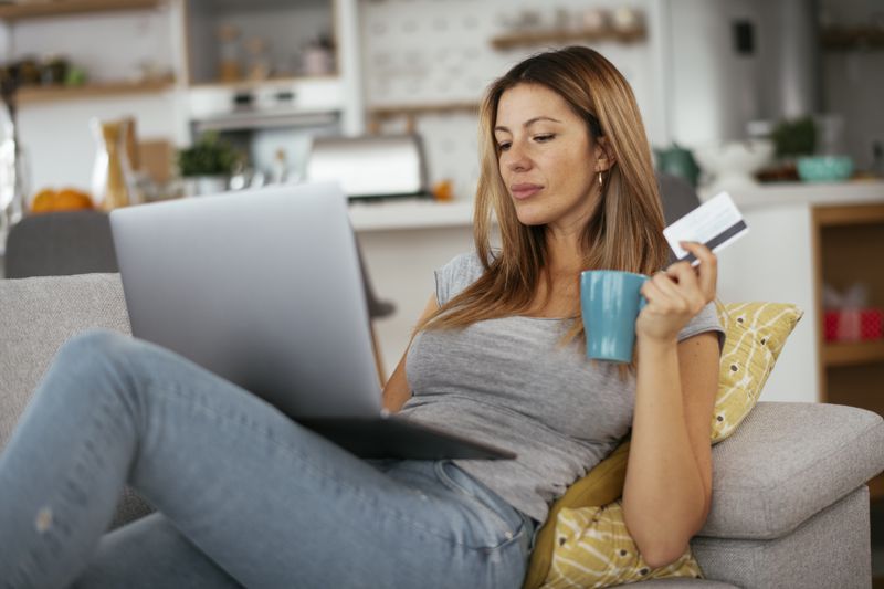 Woman making online purchase with credit card and a cup in her hand