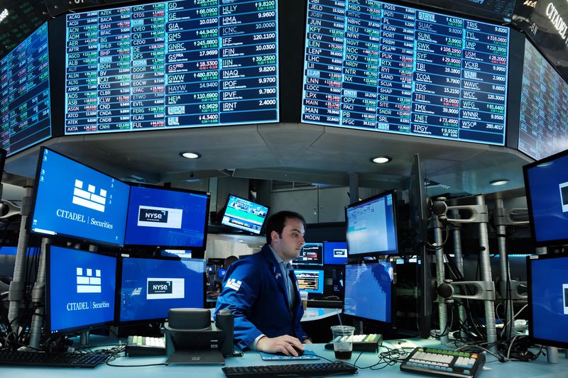 A trader works on the floor of the New York Stock Exchange surrounded by screens with stock market data