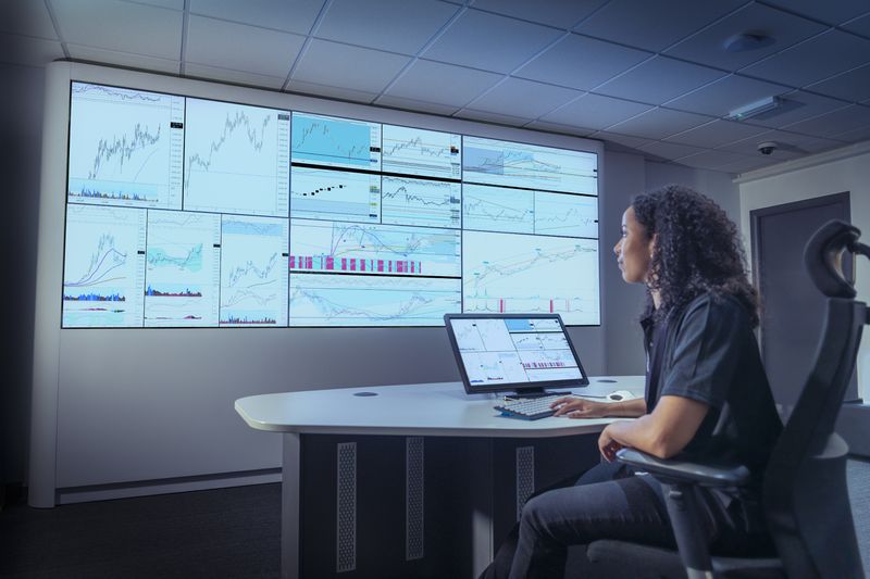 The unit trust fund manager reviews the performance of several investments that are being projected from a laptop onto a wall.