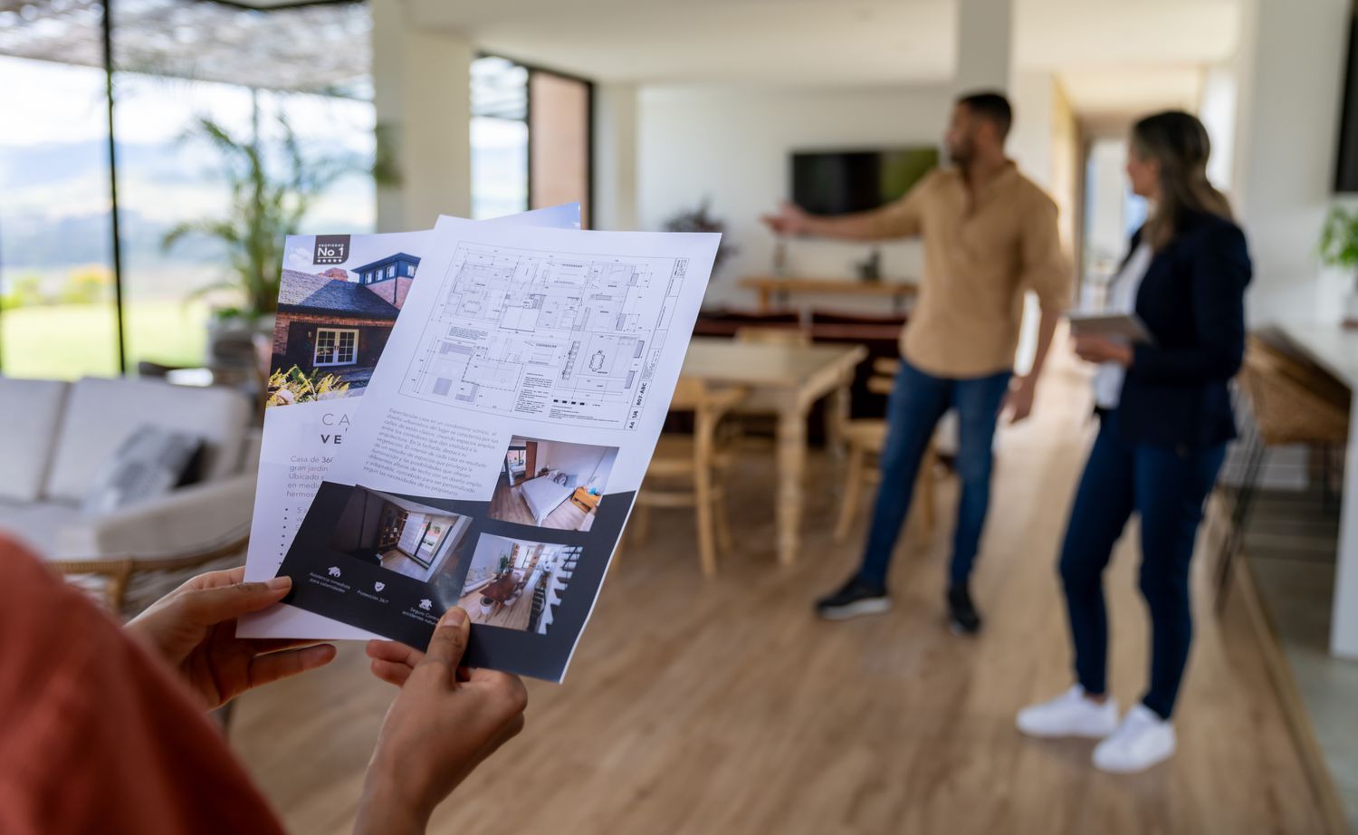 Close-up on a client looking at a house brochure at a real estate showing.