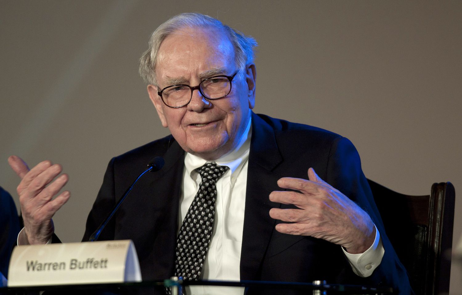 Warren Buffett gestures with his hands while speaking at a panel event