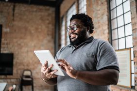 Happy investor reading news on the tablet about the higher interest rates for business CDs.