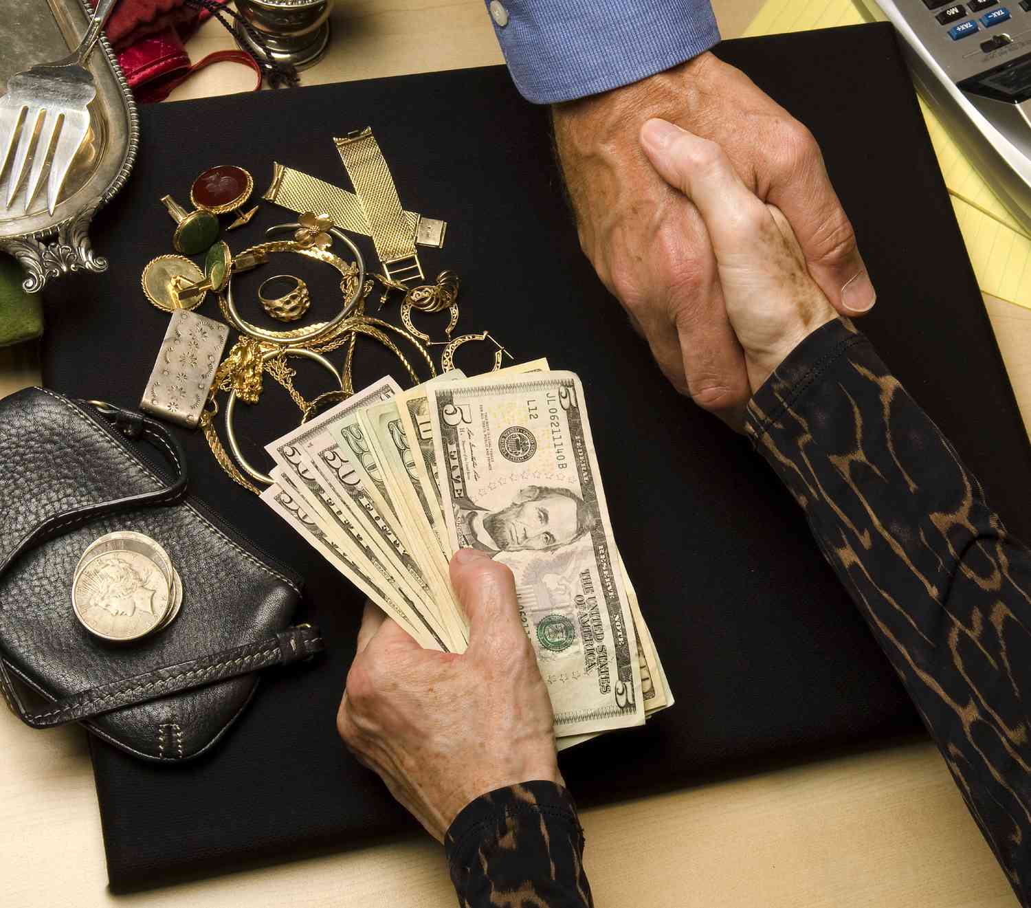 A person accepts a handful of cash as they sell old coins, jewerly, gold and silver items to a dealer.