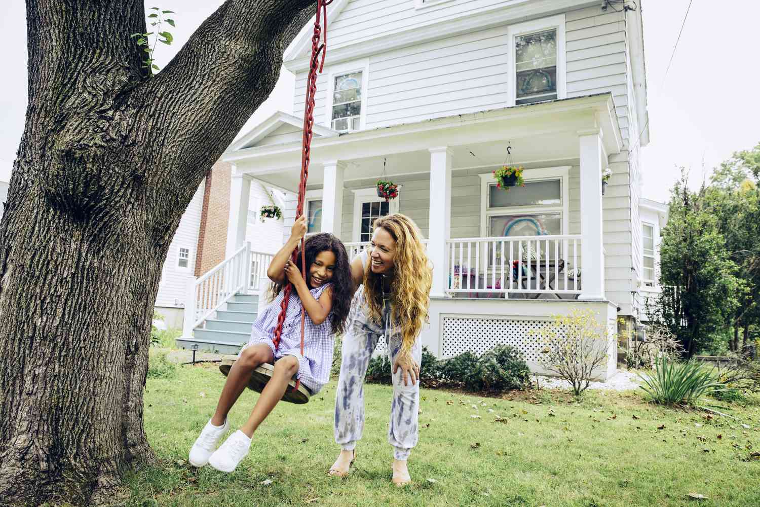 A woman pushes her daughter on a swing