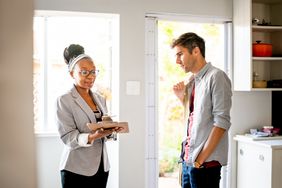Landlord holding a clipboard looking at documents with a tenant