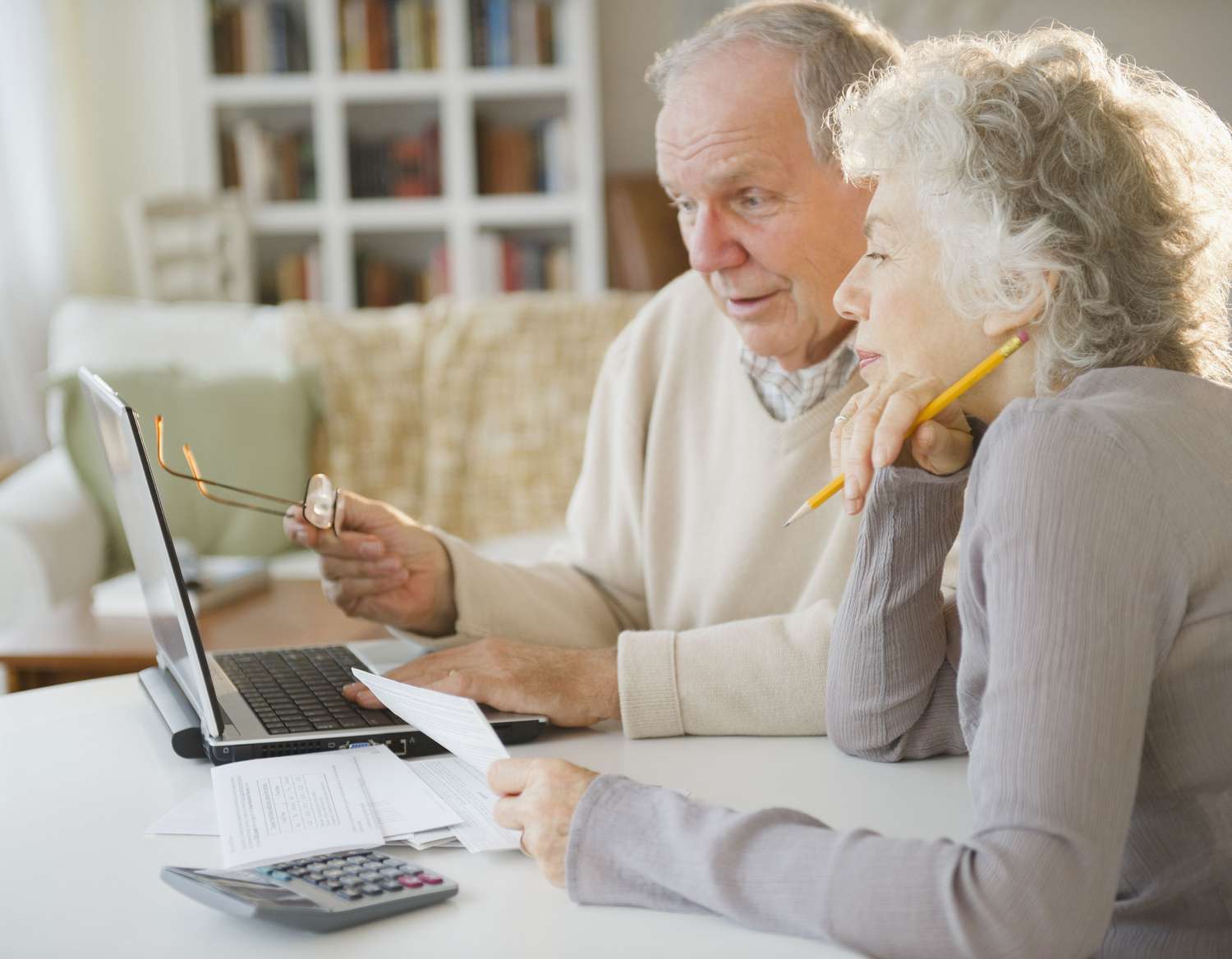 Two people seated at a table, looking at a laptop screen