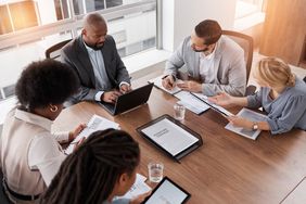 Fund managers meet around a conference room table to review the potential downside risk of the investments in a mutual fund.