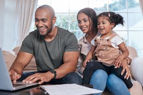 A couple with child looking for free business checking account on laptop.