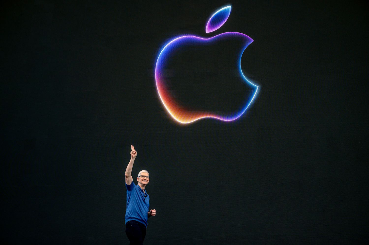 Tim Cook, chief executive officer of Apple, speaks on stage beneath a colorful Apple logo. 