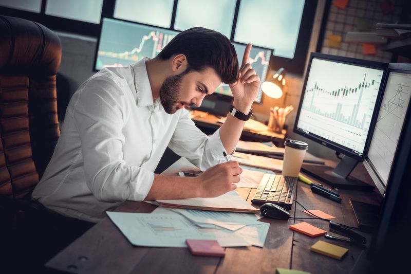 A businessman trader got a new business idea while sitting at a desk full of computer monitors.